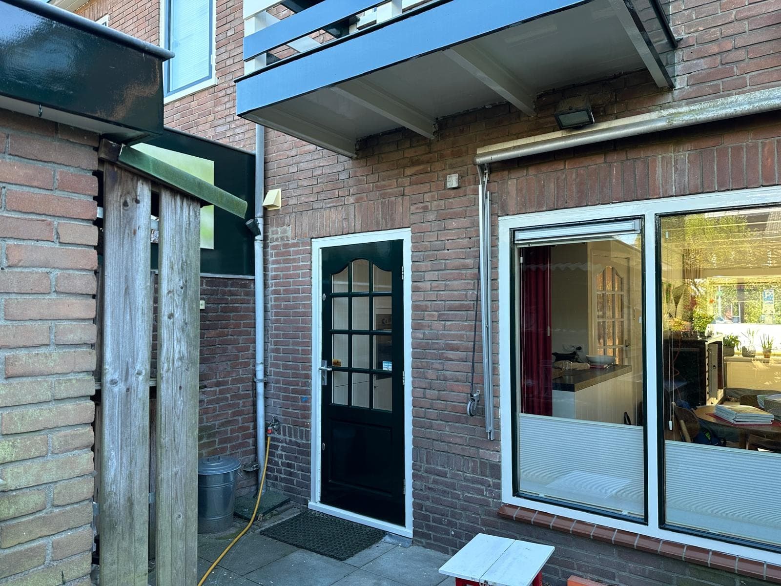 Zwarte achterdeur met glas in wit kozijn naast de tuinpui