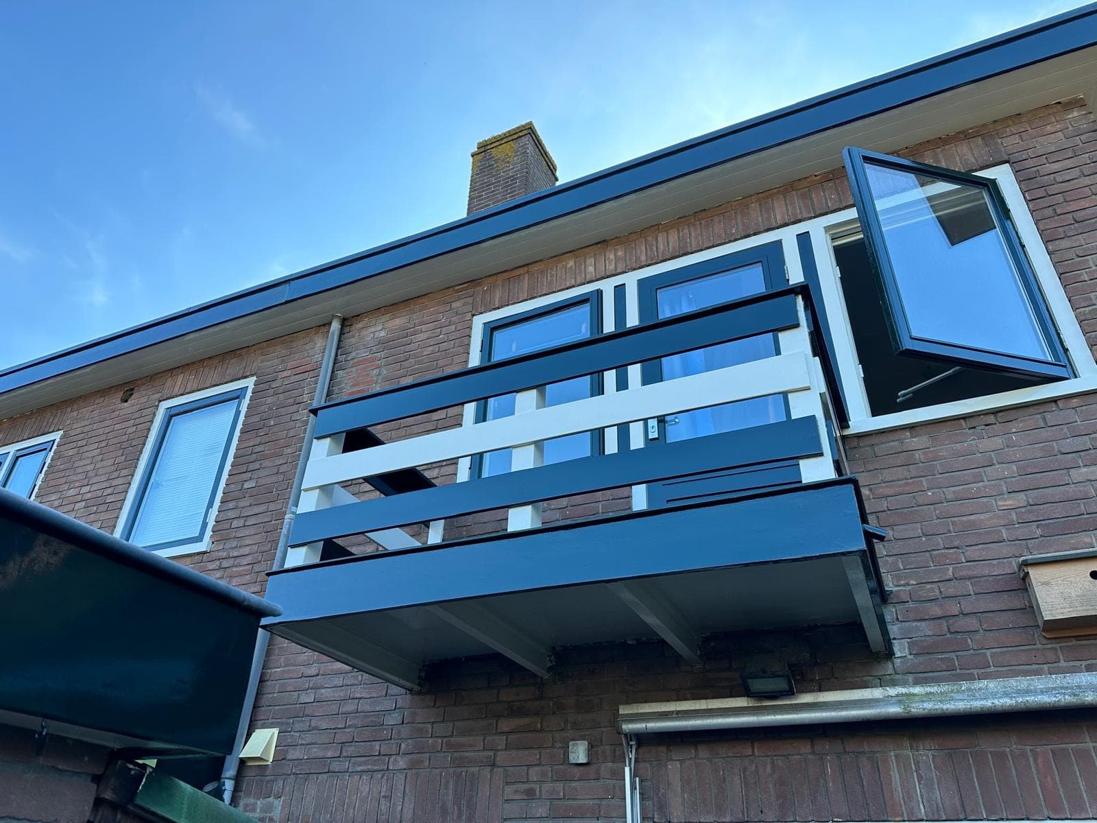 Balkon met wit hek en donkergroene rand aan de achtergevel van een jaren-30 woning