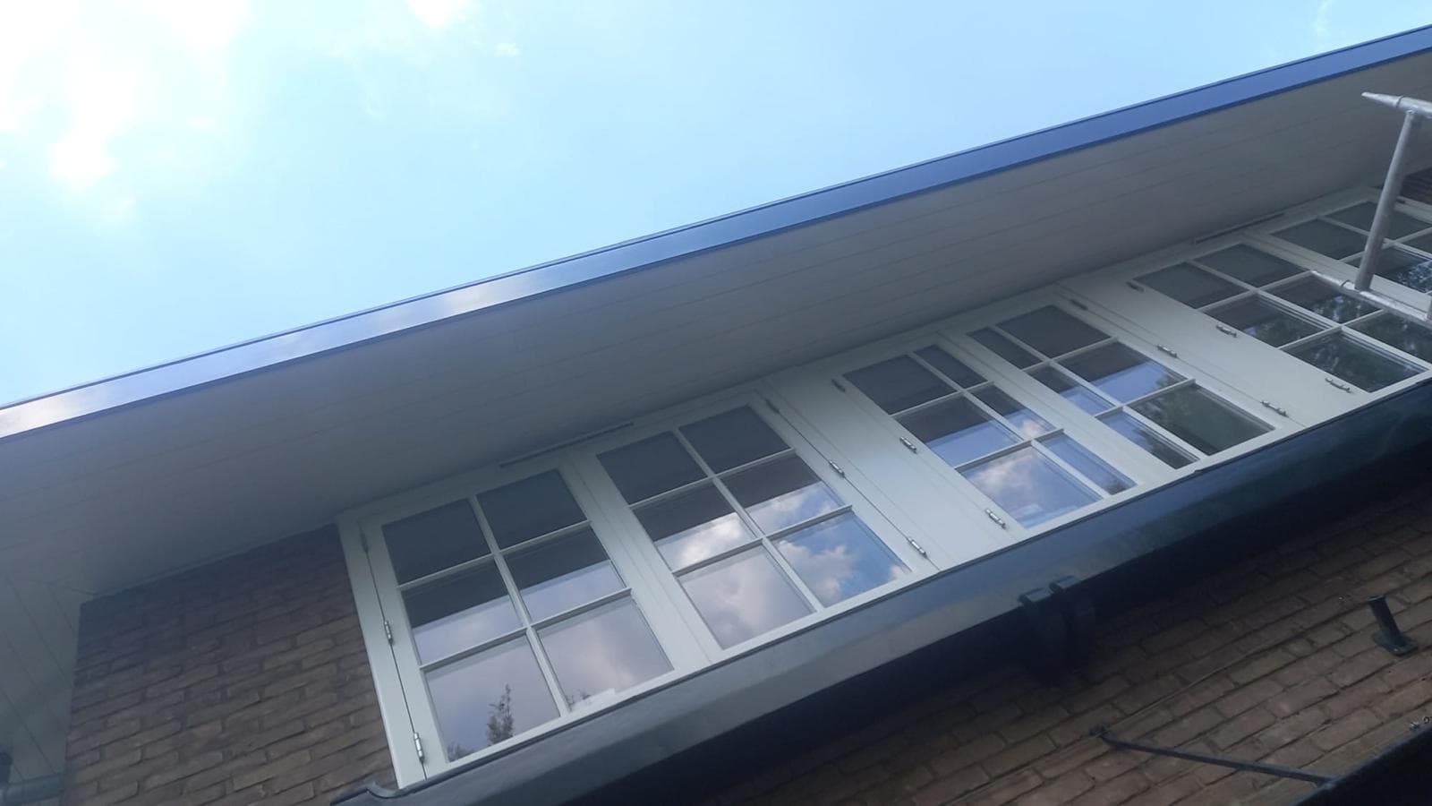 Afgewerkte dakrand en kozijnen tegen een blauwe lucht