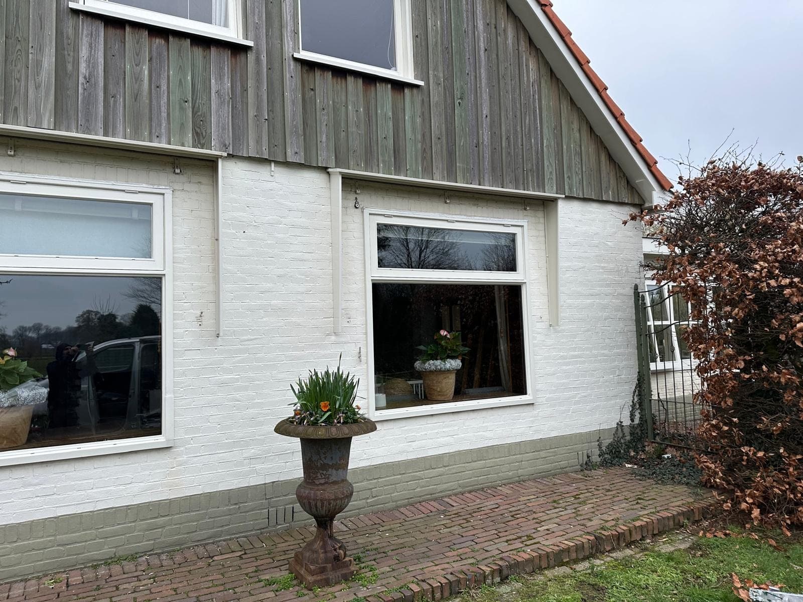 Twee grote witte kozijnen met bovenlicht in een witgeschilderde bakstenen gevel