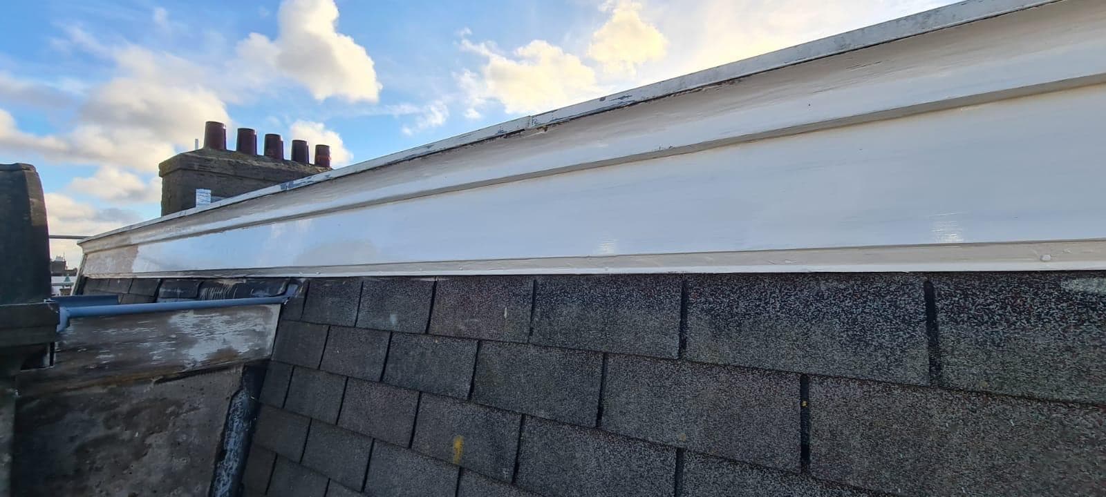 Het geschilderde boeideel langs de dakrand tegen een blauwe lucht