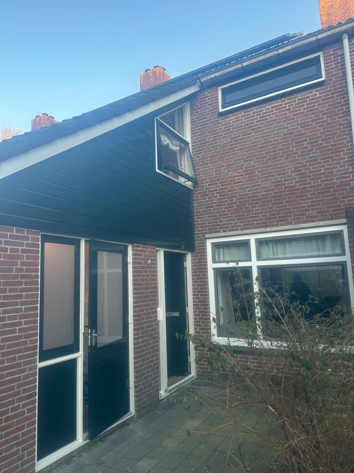 Overzicht van de groene topgevel met dubbele deuren, voordeur en wit kozijn