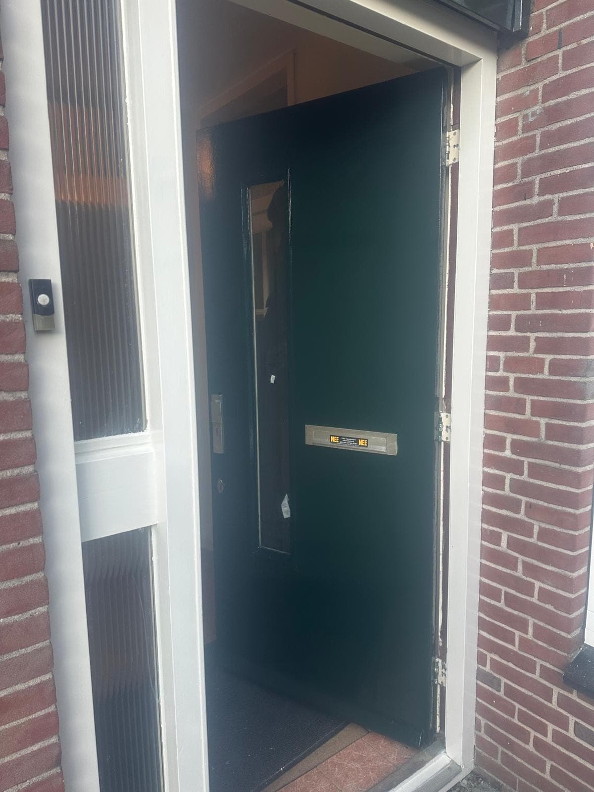 Donkergroene voordeur met brievenbus in een wit kozijn