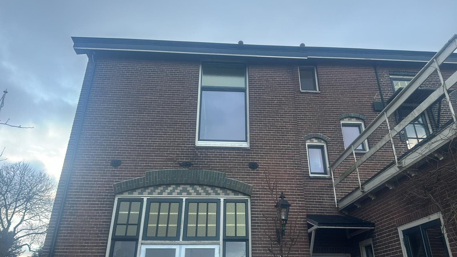 Achtergevel van het herenhuis met het boogkozijn en de steiger ernaast