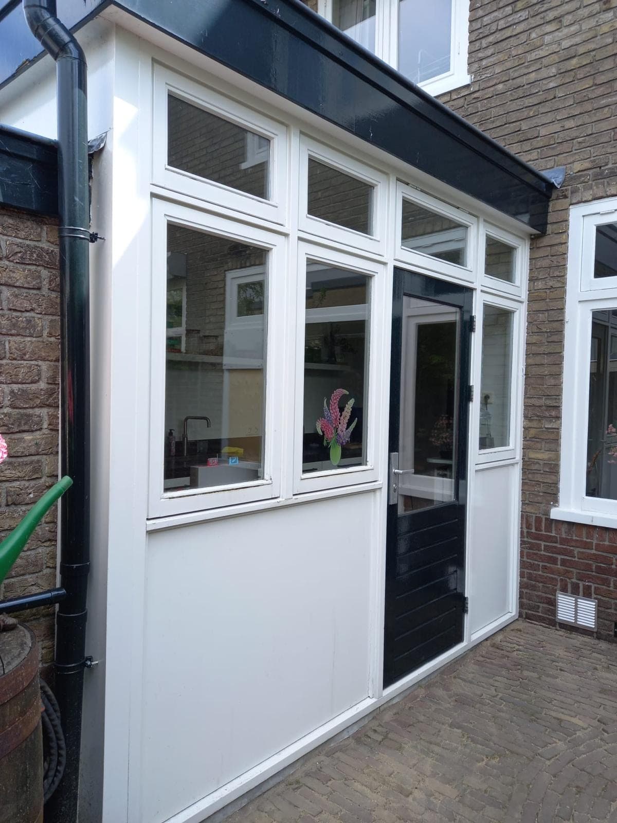 Witte houten glaswand met bovenlichten en een donkergroene achterdeur