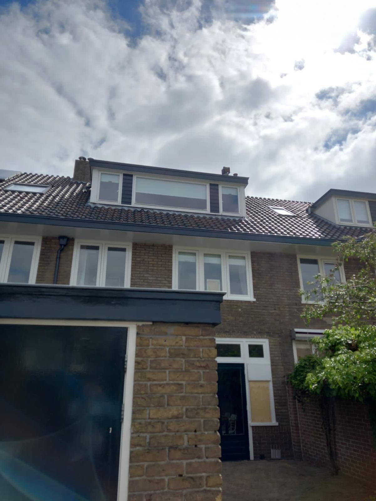 Achtergevel van de jaren-30 woning met dakkapel, witte kozijnen en een gemetselde aanbouw