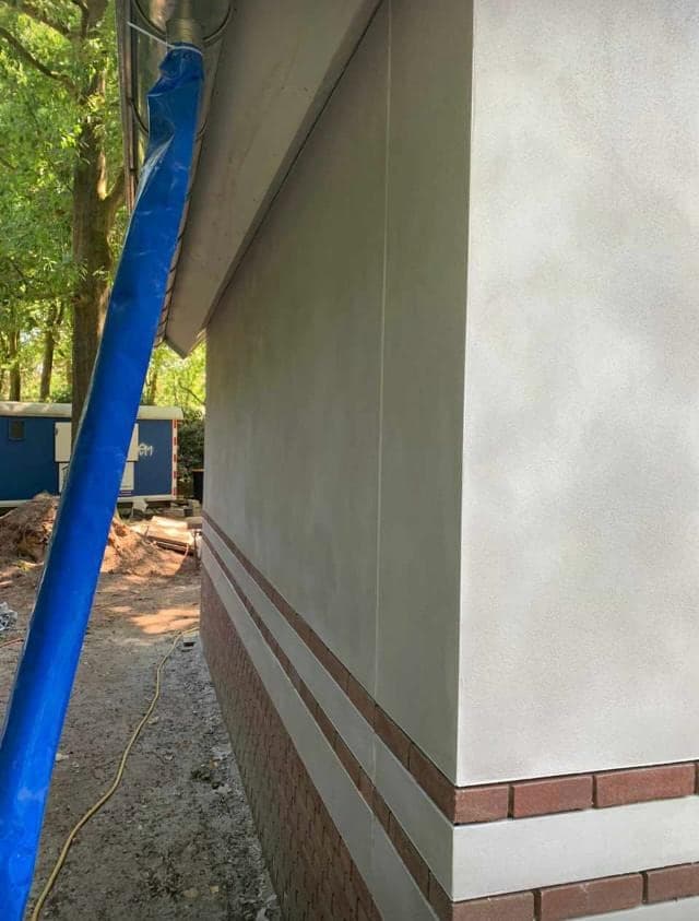 Zijgevel van het koetshuis, gestuukt, met de tuin op de achtergrond
