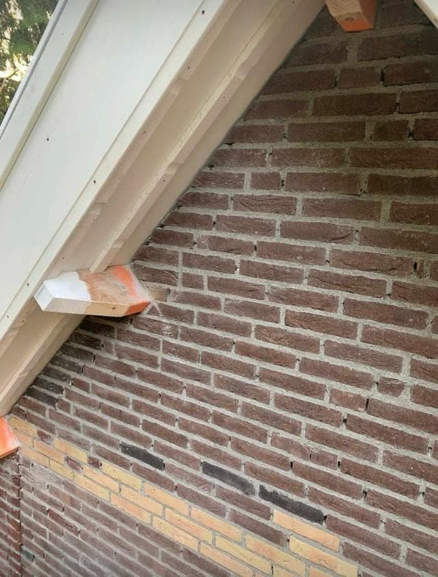 Hoek van het koetshuis met opnieuw gevoegd metselwerk onder het dakoverstek