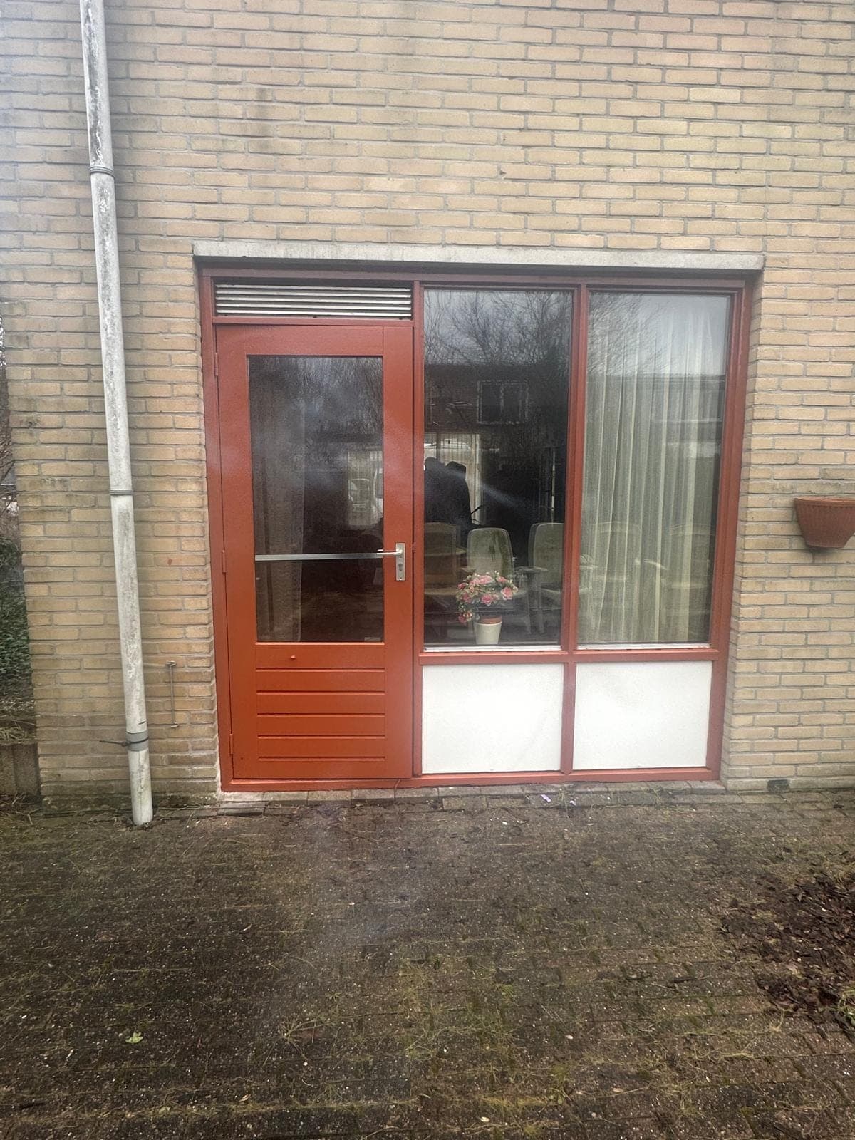 Roodbruine tuindeur met pui en witte borstweringspanelen in gele baksteen