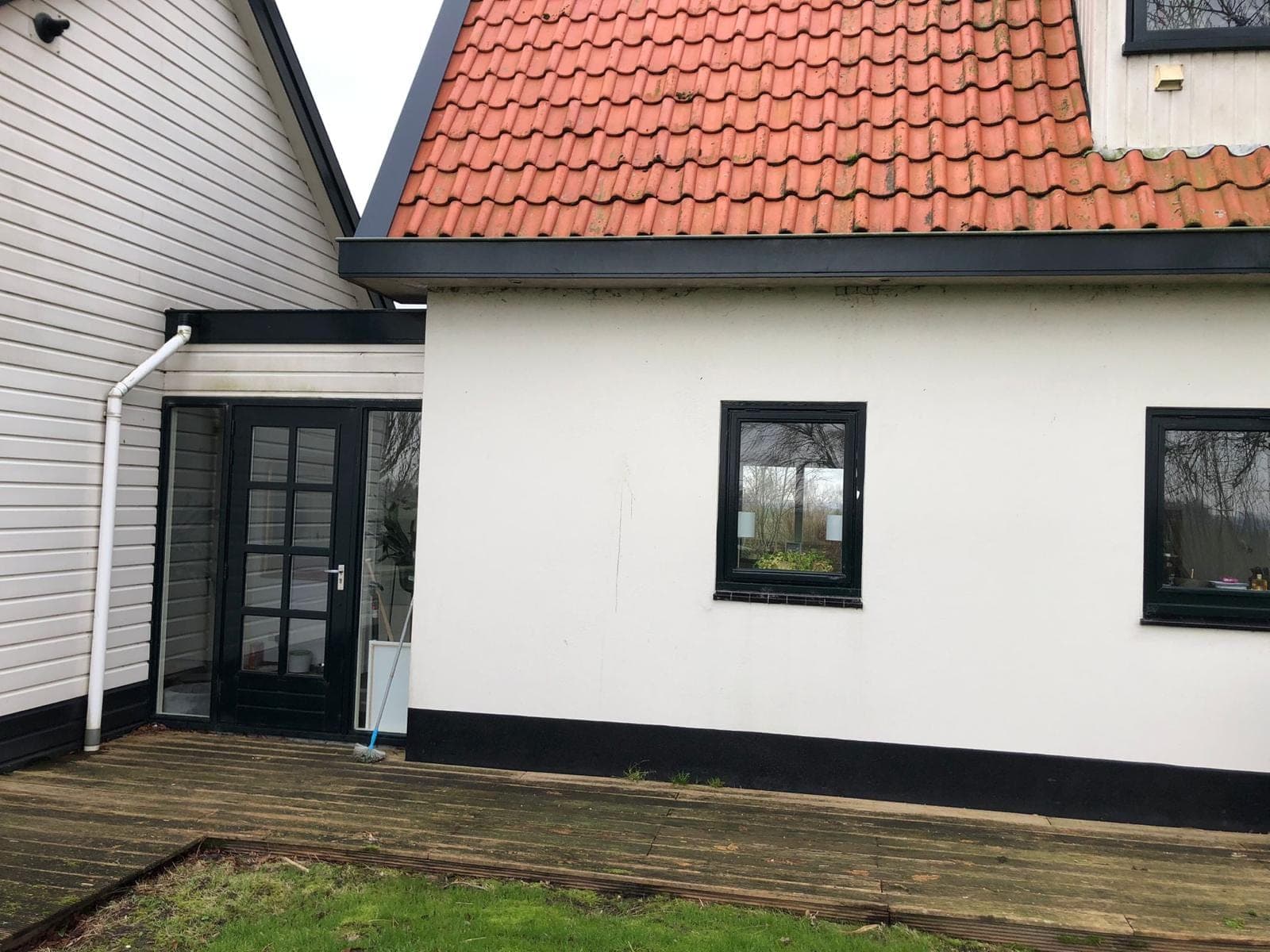 Tussenlid tussen twee woningdelen met zwarte deur en witte regenpijp